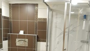 Een badkamer met toilet, douchecabine en bruine betegelde vloer.