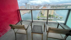 A balcony with two chairs and a table, overlooking a marina and cityscape. - New! Upper Studio Getaway Resort-Style Living (Hallandale Beach)