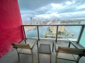 A balcony with two chairs and a table, overlooking a marina and cityscape. - New! Upper Studio Getaway Resort-Style Living (Hallandale Beach)