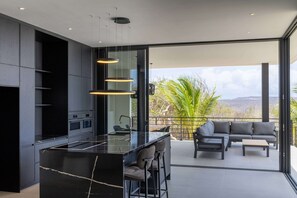 Eine moderne Küche mit Kochinsel, Barhocker und einem Essbereich mit Sofa und Tisch.