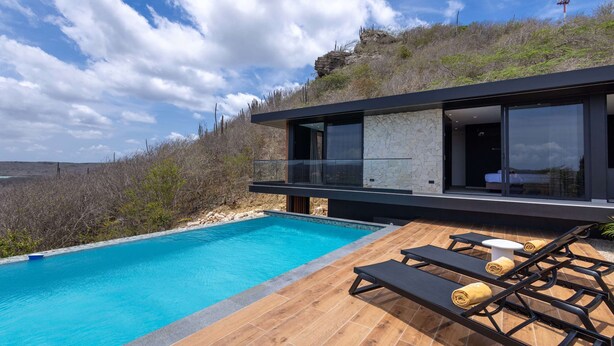Una casa moderna con piscina, muebles de exterior y vistas del paisaje circundante.