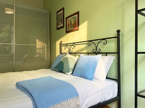 A bed with a metal frame, white bedding, and a blue throw blanket. - Casa Nicole - Fine Stay in Navigli District (Milan)