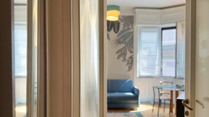 A doorway leading to a room with a patterned rug, a blue sofa, and a dining table. - Casa Nicole - Fine Stay in Navigli District (Milan)