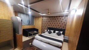 Un dormitorio moderno con cama, sofá, una mesita y ventilador de techo.
