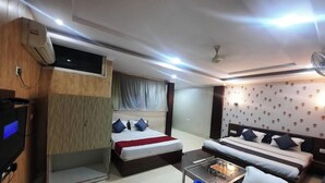 Una habitación de hotel con cama, sofá, televisión y ventilador de techo.