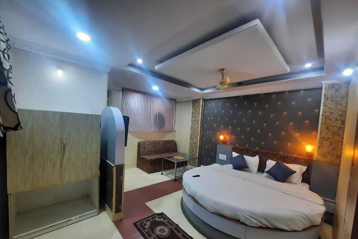 Un dormitorio con cama, sofá, una mesita y un armario.
