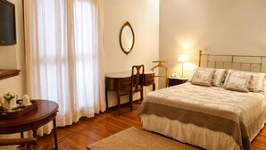 A bedroom with a bed, bedside table, lamp, chair, and a small table with a tray.
