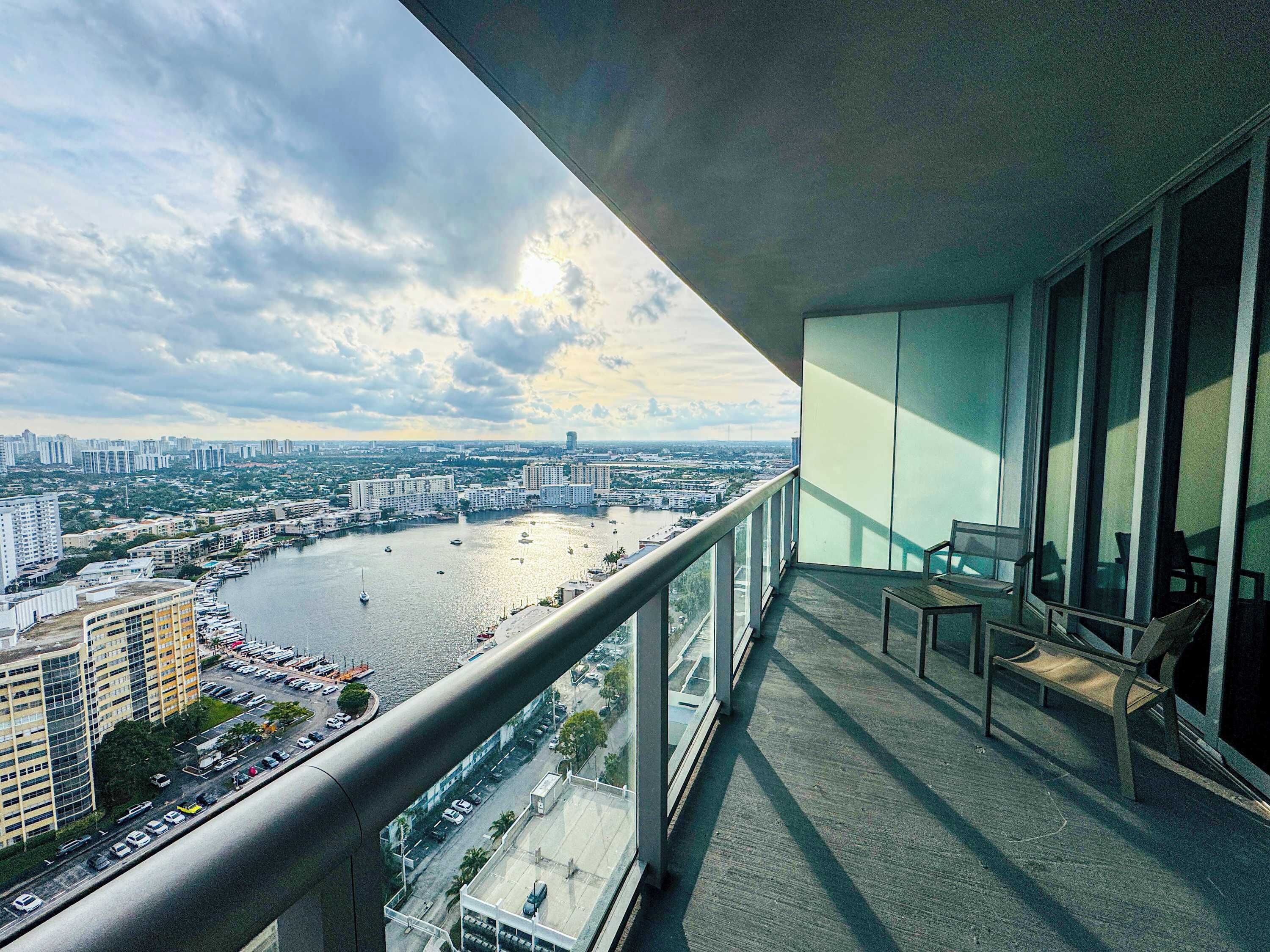 A balcony with a view of a cityscape, including buildings and a body of water.