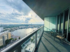 A balcony with a view of a cityscape, including buildings and a body of water. - Top-Floor Intracoastal · 2BR Beachwalk Resort (Hallandale Beach)
