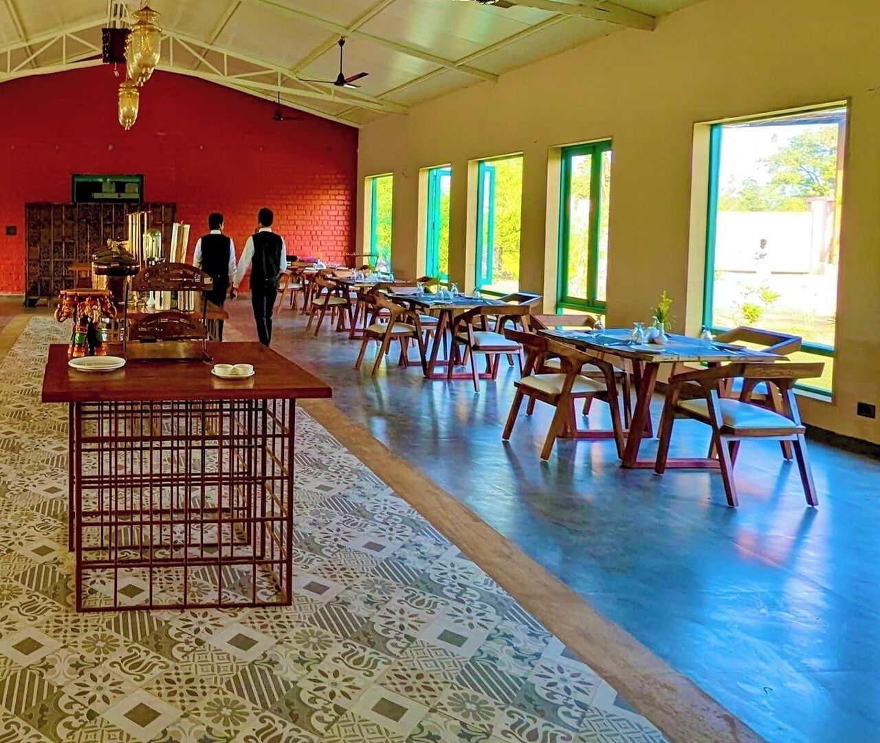 A spacious hall with long tables and chairs, large windows, and a patterned floor.