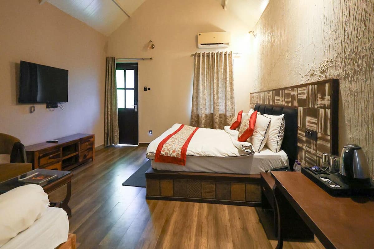 Un dormitorio con cama, televisión, escritorio y aire acondicionado.