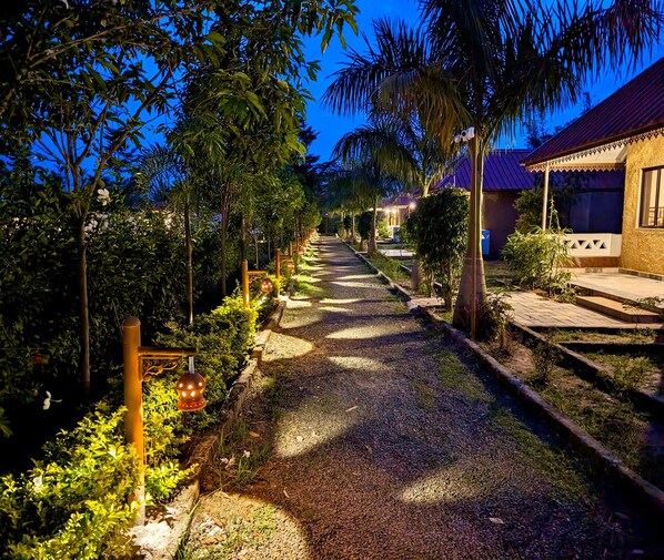 A pathway lined with trees and a building with a tiled roof.
