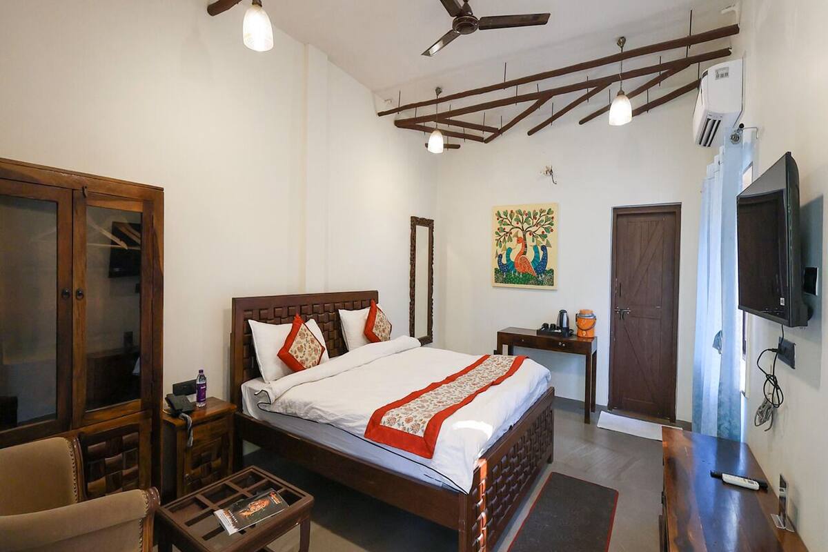 Un dormitorio con cama de madera, un escritorio, una silla, un armario, un ventilador de techo y un televisor.