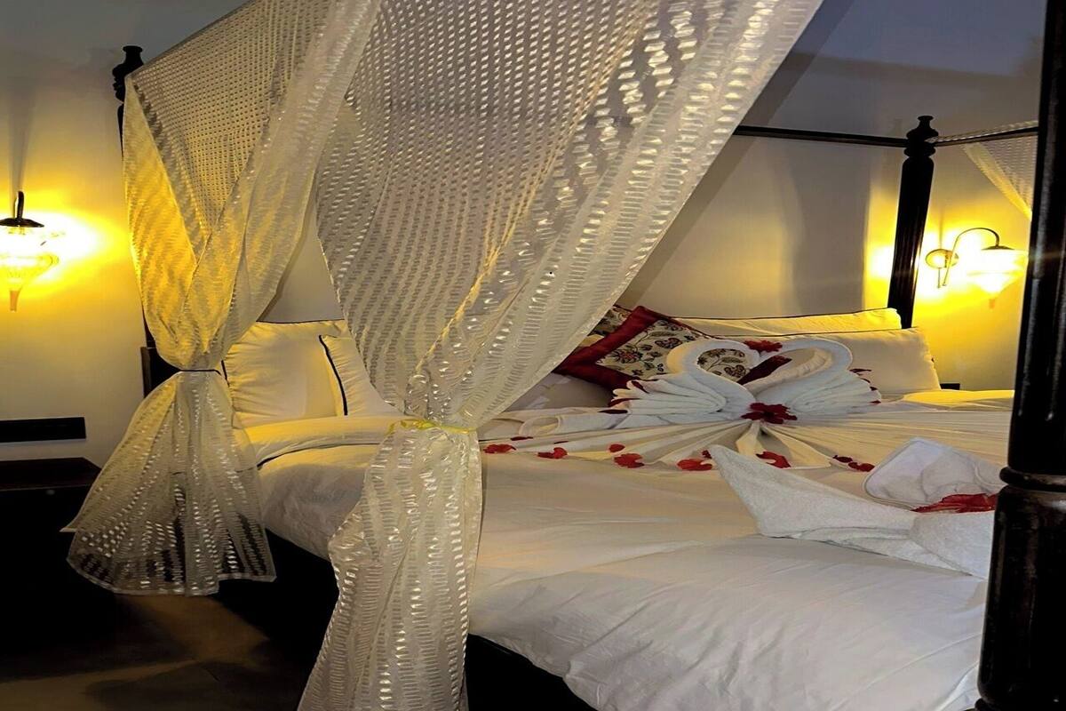 Una cama con dosel, ropa blanca de cama y un arreglo floral.