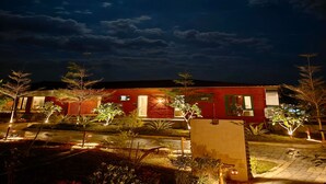 Un edificio con fachada roja, una puerta a la vista y un ventanal pequeño.