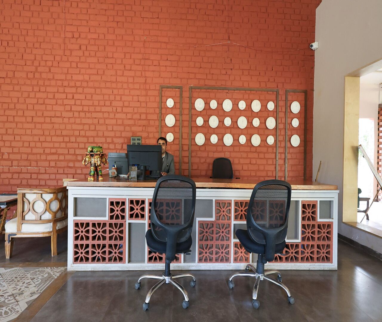 A reception desk with two chairs, a computer, and a decorative wall with circular patterns.