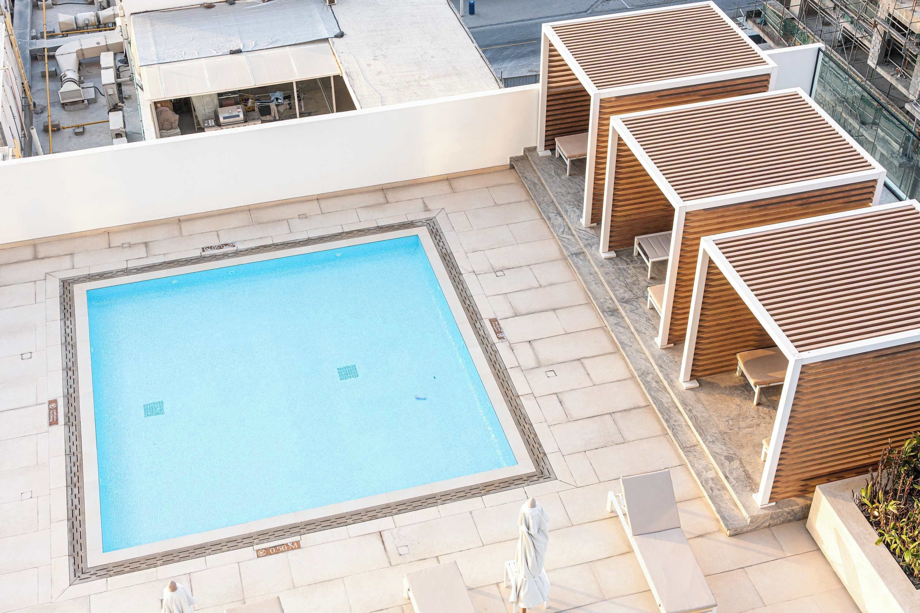 A rooftop pool with wooden loungers and a clear blue pool.