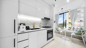 Eine moderne Küche mit weißen Schränken, einem eingebauten Backofen und einem Essbereich mit Tisch und Stühlen.