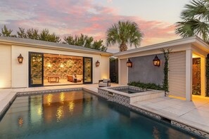 A modern house with a swimming pool, a patio with outdoor furniture, and a large glass door leading to an interior space. - Maison Barnard | Starland's Most Stunning Home + Private Pool, Event Space (Savannah)