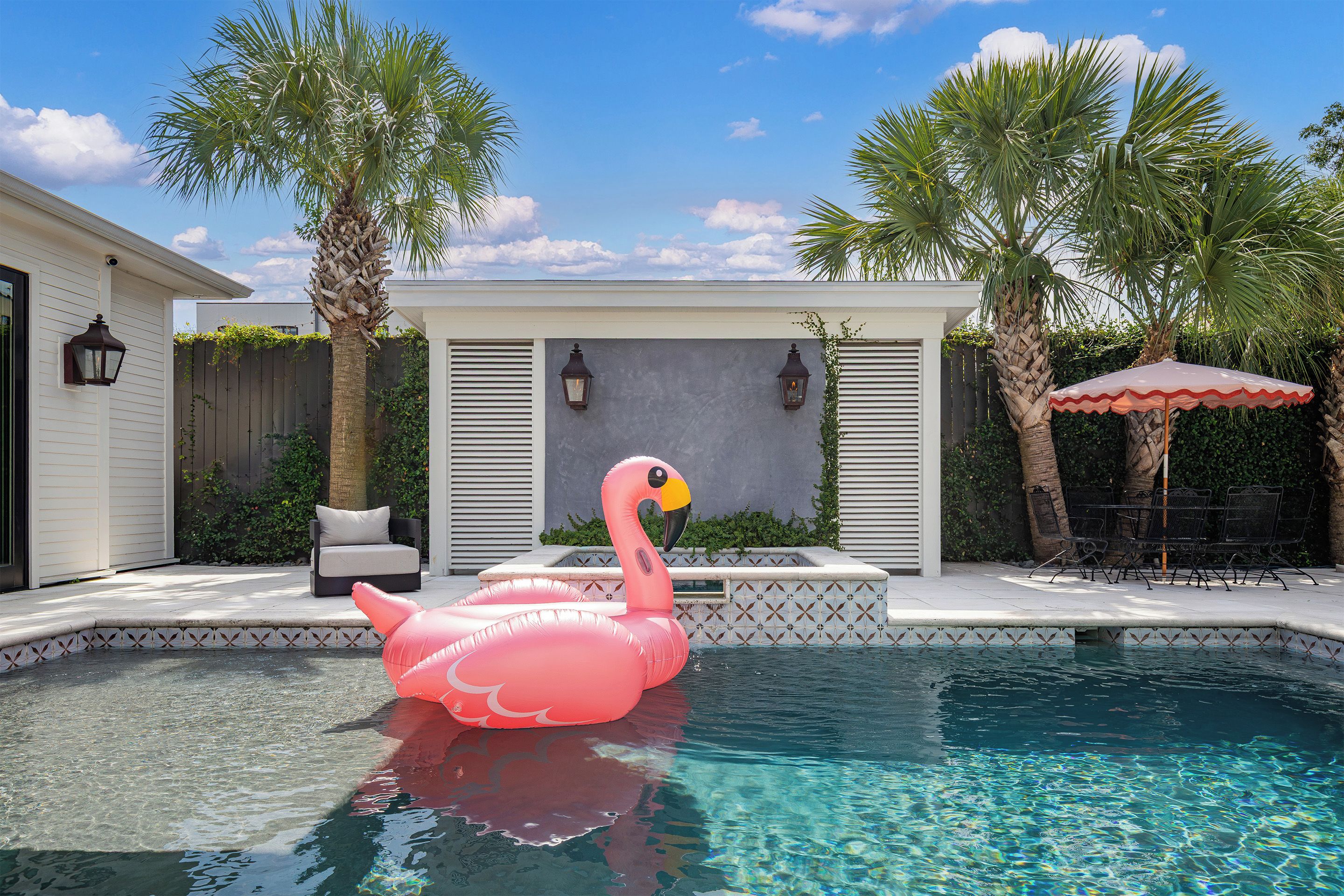 Una piscina con un flotador de flamenco rosa, una silla de descanso y una sombrilla.