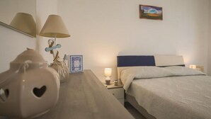 A bedroom with a bed, bedside lamps, a nightstand, a decorative vase, and a framed picture on the wall. - Apartment 8 with Sea View, Wi-Fi and Air Conditioning (Paestum)