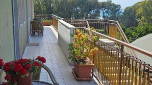 A balcony with wicker furniture, potted plants, and a view of trees. - Apartment 8 with Sea View, Wi-Fi and Air Conditioning (Paestum)
