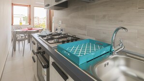 A modern kitchen with a gas stove, stainless steel sink, and a window with a view of buildings. - Apartment 8 with Sea View, Wi-Fi and Air Conditioning (Paestum)