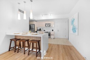 A modern kitchen with a central island, stainless steel appliances, and pendant lighting. - Cozy 2BR Apartment - Balcony & Pool (Hallandale Beach)