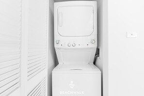A white, compact washer and dryer unit with a control panel featuring multiple settings. - Beachwalk 1BR King Bed & Resort Access (Hallandale Beach)