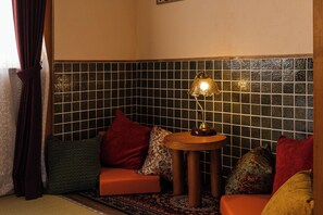 A cozy seating area with a small table, a lamp, and a patterned rug. - Hakugetsu (Nara)