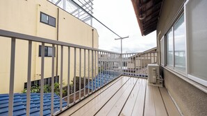 A balcony with a metal railing, wooden floor, and a view of neighboring buildings. - Hakugetsu (Nara)