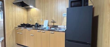 A kitchen with wooden cabinets, a black refrigerator, a stove, and a microwave.