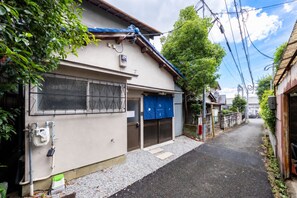 Una calle residencial estrecha con casas a ambos lados, una puerta de garaje azul y líneas de electricidad aéreas.