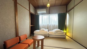 A room with tatami flooring, a futon bed, a wooden table, and a sofa. - Hakugetsu (Nara)