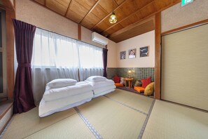 A traditional Japanese-style room with tatami flooring, a futon bed, and a sliding door. - Hakugetsu (Nara)