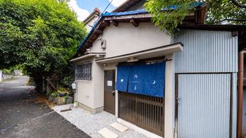 A residential building with a closed garage door, a small entrance gate, and a pathway leading to the entrance.