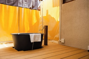 A bathroom with a black bathtub, wooden flooring, and a towel hanging on the side. - Hakugetsu (Nara)