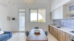 A modern kitchen with a dining table, chairs, a large window, and a blue and white tiled backsplash. - Apartment 'Baia Dei Sogni - Aqua' with Sea View, Wi-Fi and Air Conditioning (Patù)