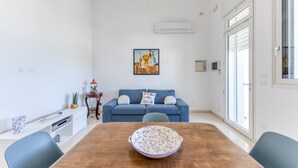 A modern living room with a dining table, sofa, and artwork on the wall. - Apartment 'Baia Dei Sogni - Aqua' with Sea View, Wi-Fi and Air Conditioning (Patù)