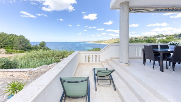 Varanda com vista para o mar, mobiliário de exterior e área de refeições.