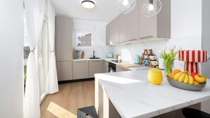 Una cocina moderna con encimera de mármol, frutero y hervidor.