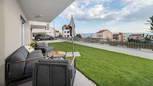 Un balcón con mobiliario exterior, vista a la calle y una zona ajardinada.