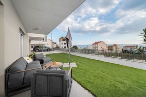 Un balcon avec du mobilier d’extérieur, une vue sur la rue et un espace gazonné.