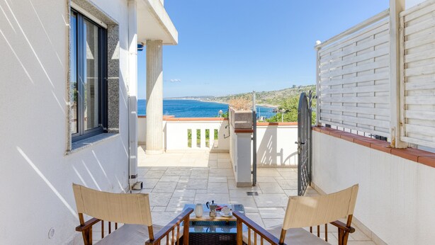 A balcony with a view of the sea, a table with chairs, and a window. - Apartment 'Baia Dei Sogni - Petra' with Sea View, Wi-Fi and Air Conditioning (Patù)