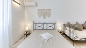 A bedroom with a bed, bedside tables, wall-mounted air conditioning, and a macrame wall hanging. - Apartment 'Baia Dei Sogni - Petra' with Sea View, Wi-Fi and Air Conditioning (Patù)