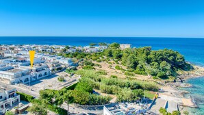 An aerial view of a coastal town with buildings, a beach, and a forested hill. - Apartment 'Baia Dei Sogni - Petra' with Sea View, Wi-Fi and Air Conditioning (Patù)