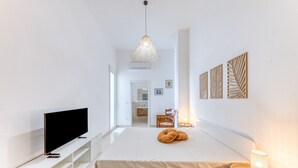 Un dormitori modern amb llit, televisió, taula de nit i làmpada.