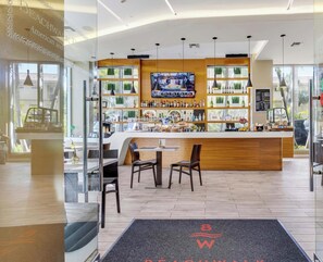 A modern bar area with a TV screen, wooden counter, and seating. - Panoramic Retreat · 2BR · Beachwalk Resort (Hallandale Beach)