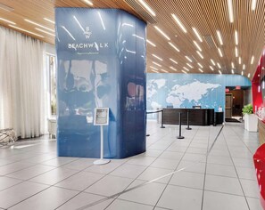 A reception area with a blue counter, a world map on the wall, and a wooden ceiling design. - Beachwalk Studio | Intracoastal + City View (Hallandale Beach)