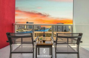 A balcony with two chairs, a table, and a bottle of wine. - Beachwalk Studio | Intracoastal + City View (Hallandale Beach)
